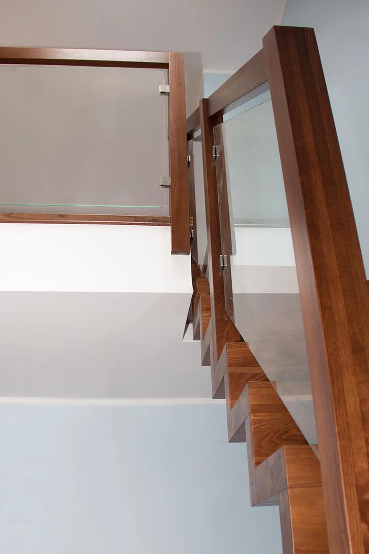 Nowoczesne schody dywanowe z jesionu, bejcowane, z balustradą szklaną