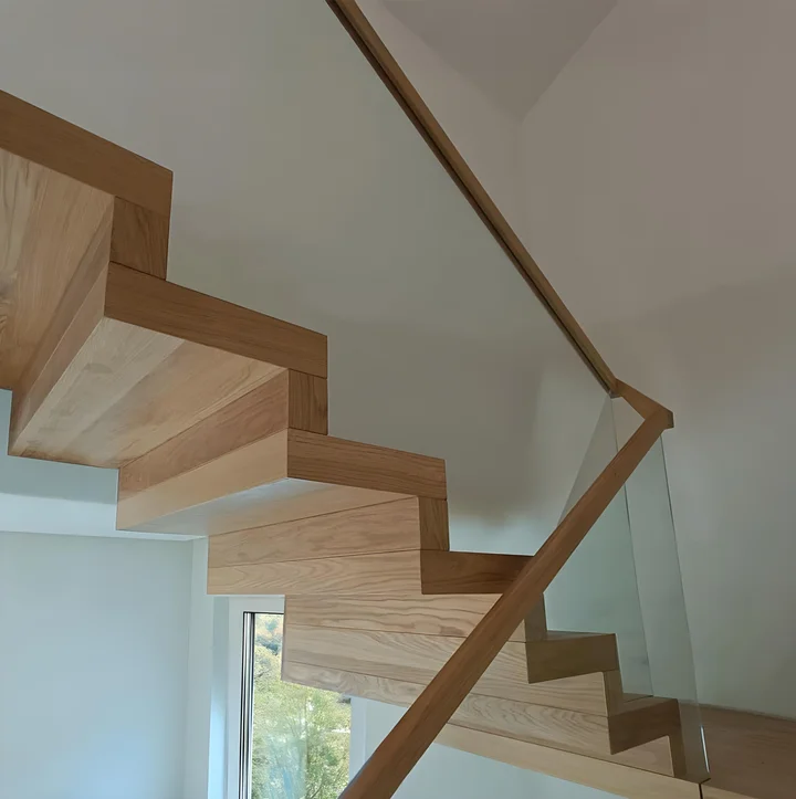 Nowoczesne schody dywanowe z podestem i balustradą szklaną