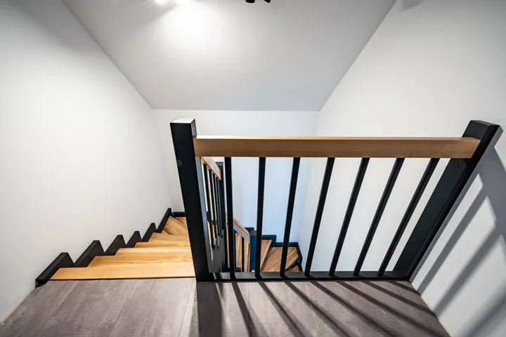 Schody policzkowe zębate z czarnymi prętami balustrady